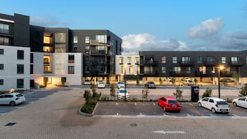 Un moderno complejo de apartamentos con varios edificios, un estacionamiento y algunos automóviles.