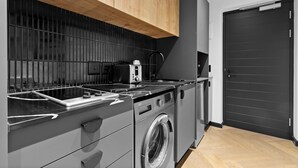 A compact kitchen with a built-in washing machine, a toaster, and wooden cabinets. - Nine Palms 214 (Cape Town)