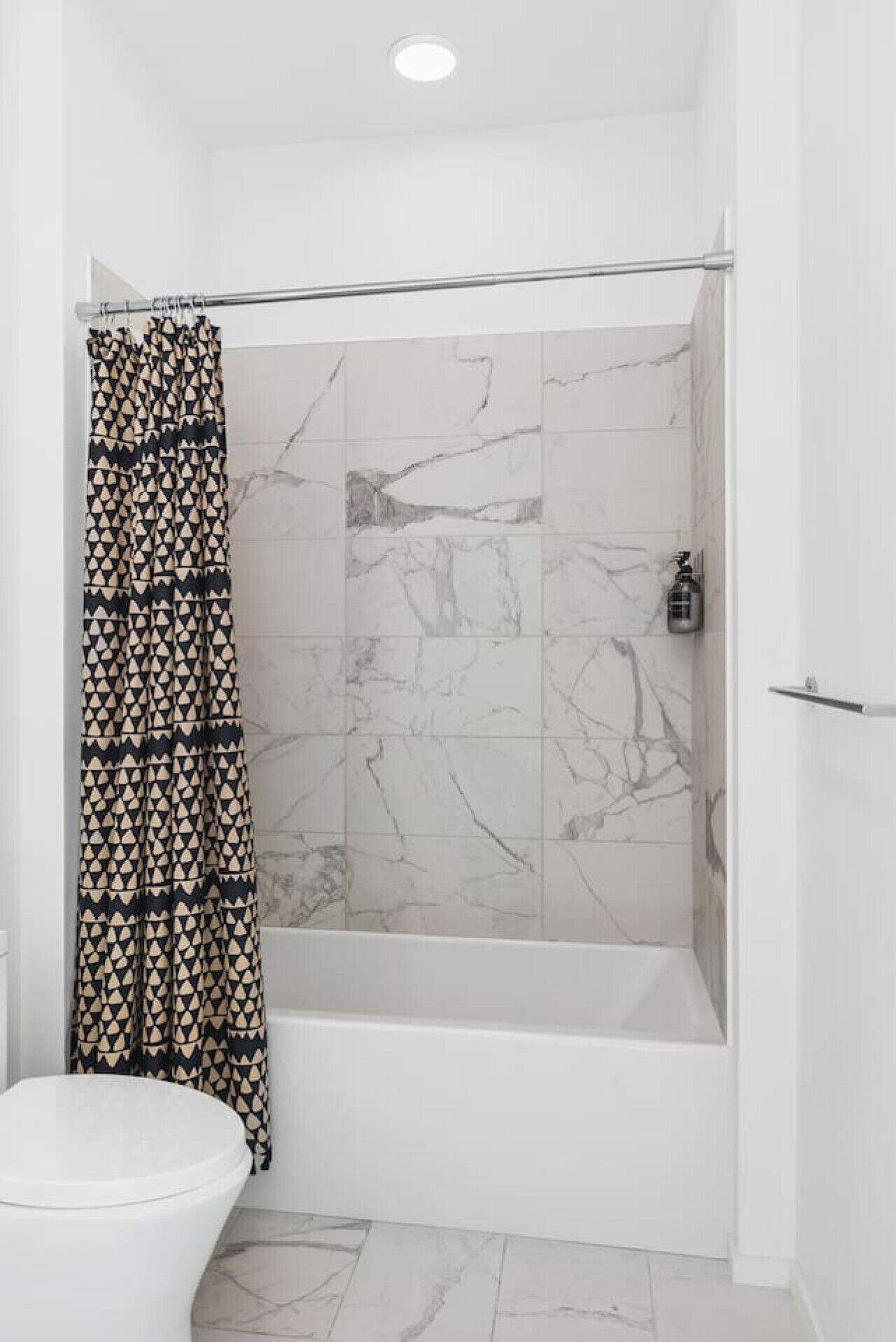 Un baño con ducha, inodoro y azulejos de mármol.