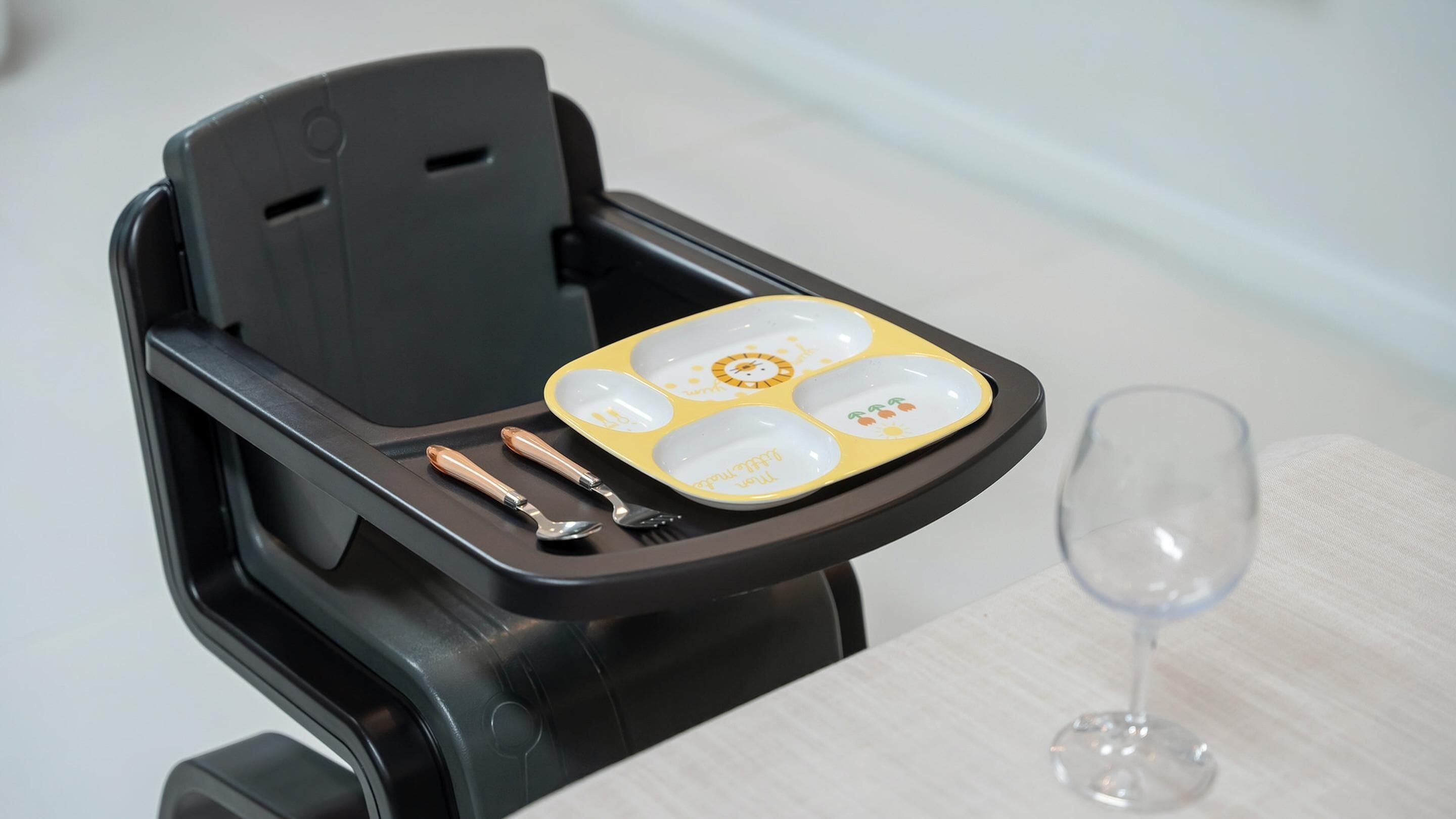 A tray table with a plate, cutlery, and a wine glass.