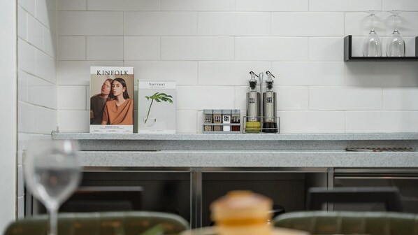 A kitchen counter with a magazine, a potted plant, and two bottles of oil.