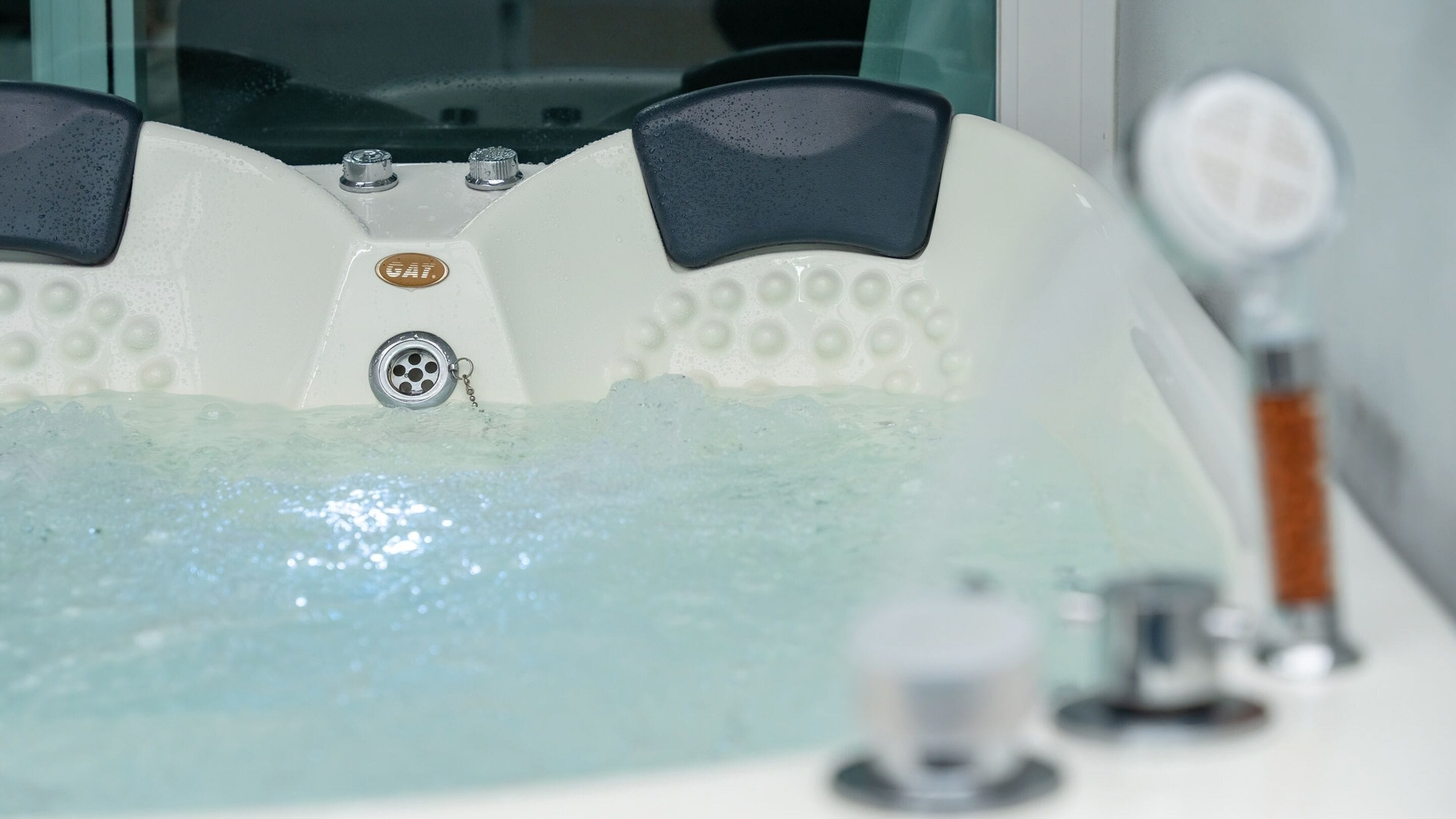Una bañera con el logo de la marca a la vista, un grifo y una llave de control.