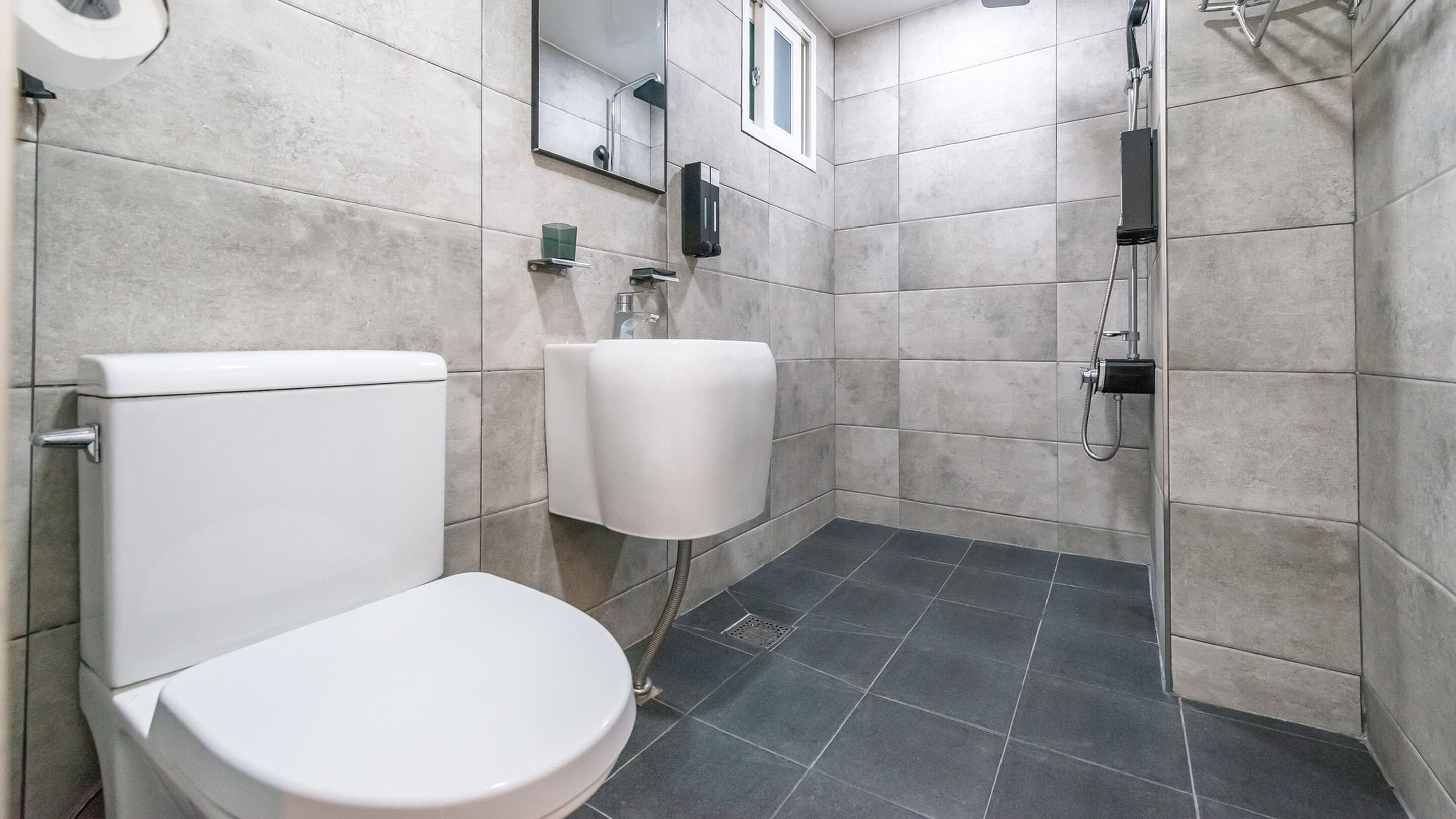 A modern bathroom with a toilet, sink, and shower.