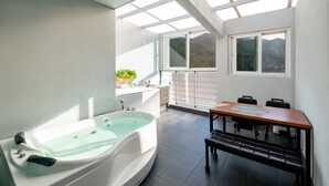 Un baño moderno con una bañera independiente, un lavamanos y una ventana con vistas a un paisaje pintoresco.