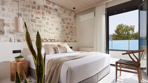 Ein modernes Schlafzimmer mit Backsteinwand, einem großen Bett, einem Holznachttisch und Blick ins Freie durch eine Schiebetür.