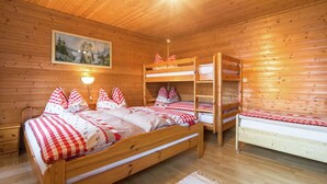 Una habitación de cabaña de madera con dos literas, una cama individual y un cuadro en la pared.