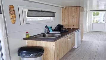 Een koelkast, een kookplaat, een koffiezetapparaat/waterkoker, eettafels