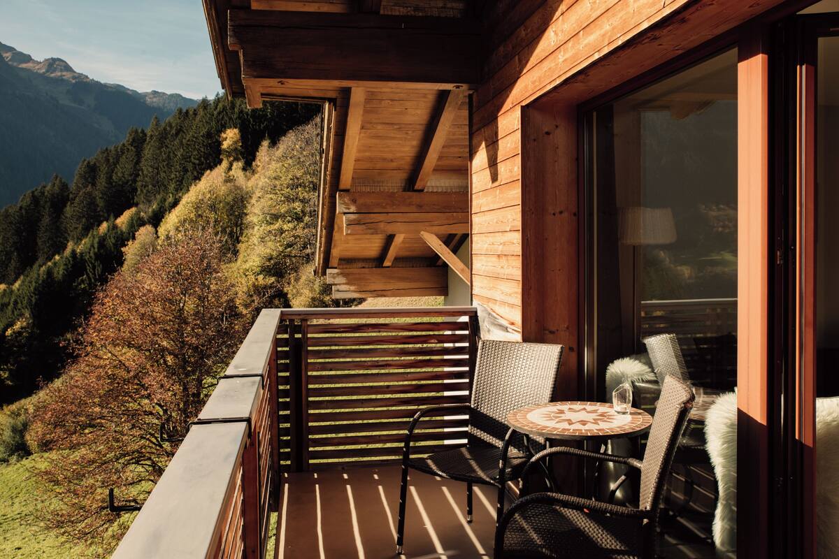 A wooden balcony with a view of a forested hillside.