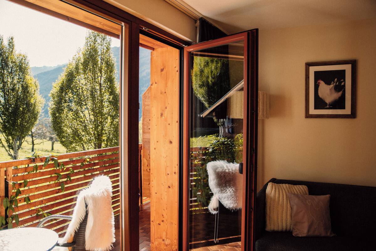 A room with a sliding glass door leading to a balcony, a sofa, and a framed picture on the wall.