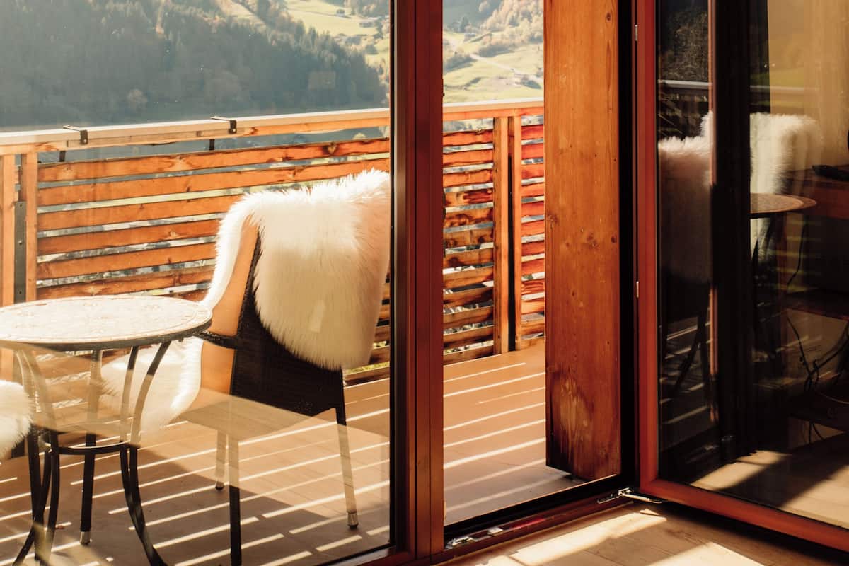 A room with a glass door leading to a balcony with a mountain view.