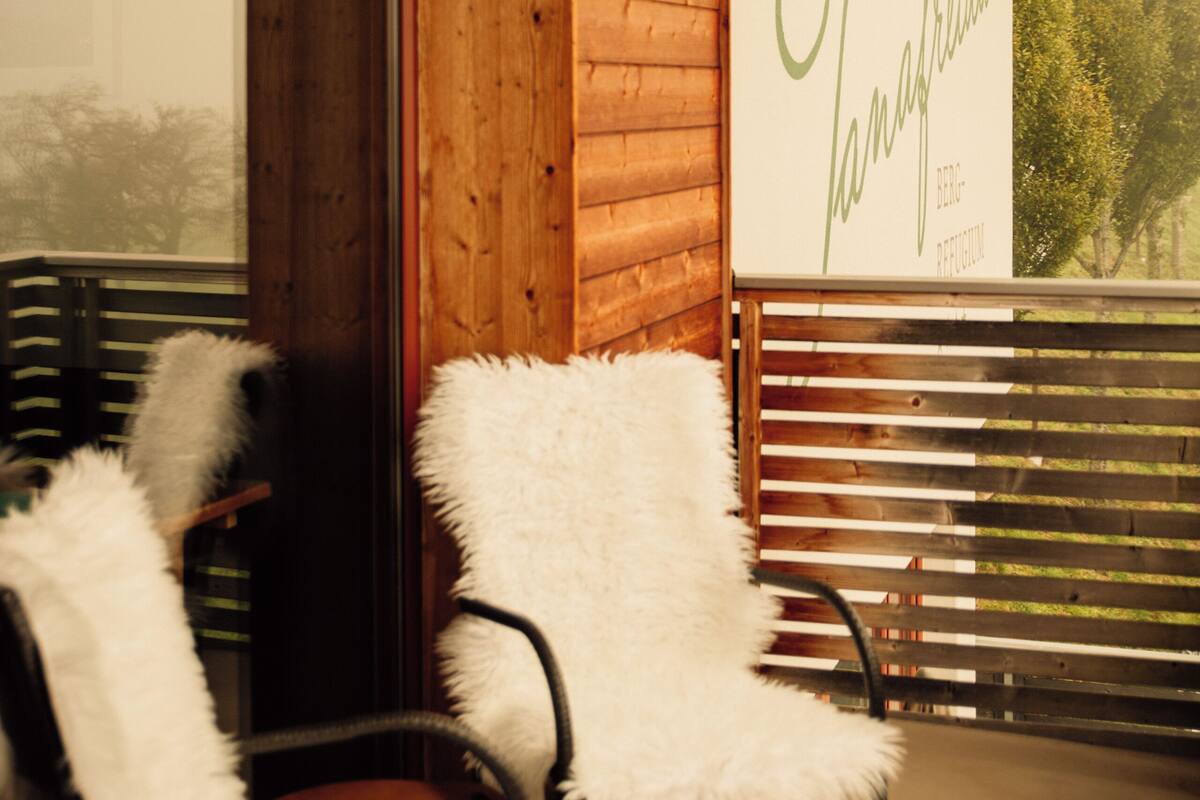 A wooden interior with two white chairs and a large window.