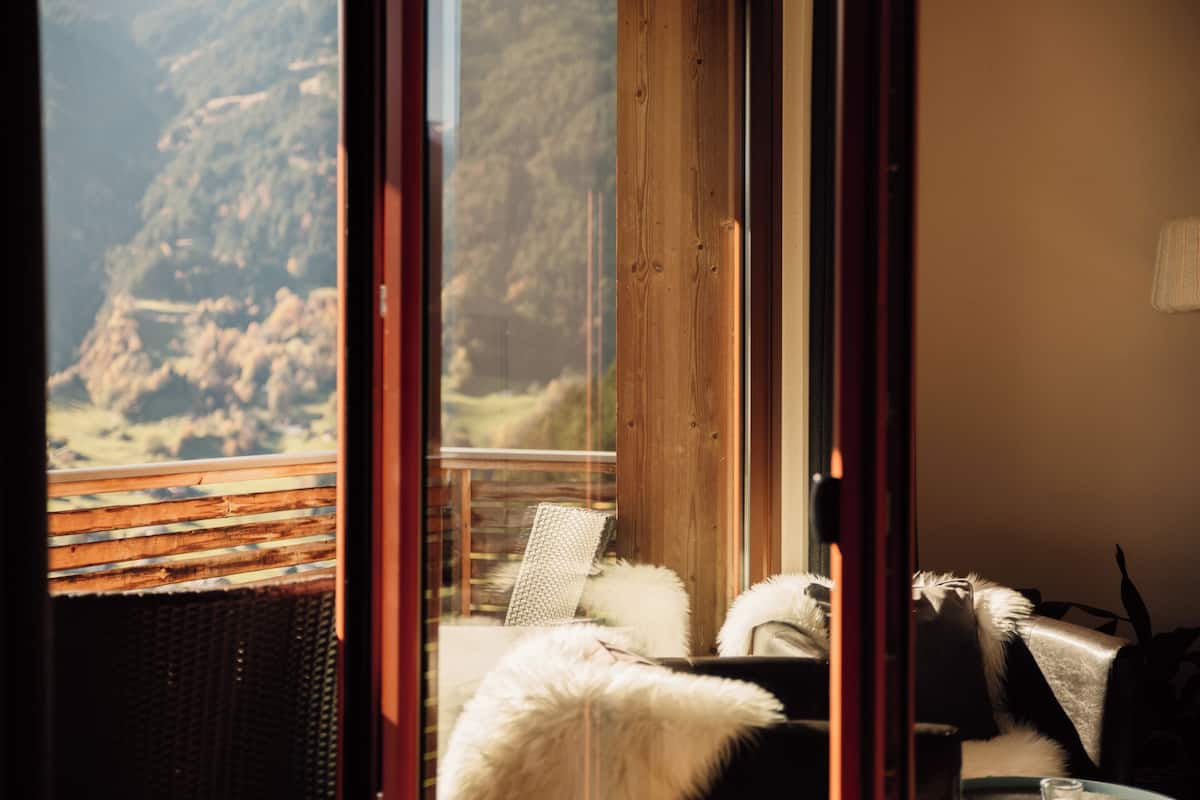A room with a view of a mountainous landscape through a glass door.