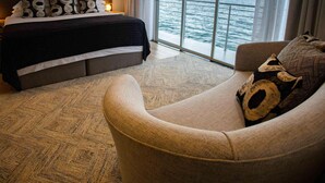 Une chambre à coucher avec un lit, un canapé et une grande fenêtre donnant sur la mer.