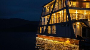 Un bateau à plusieurs niveaux, doté de balcons illuminés et d’une ligne de flottaison visible.