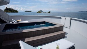 Un jacuzzi sur le pont d’un bateau, avec vue sur la mer et les îles.