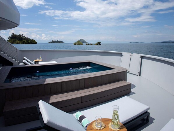 Un jacuzzi en la cubierta de un barco con vistas al mar y a las islas.