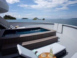 Ein Whirlpool auf einem Bootsdeck mit Blick auf das Meer und Inseln.
