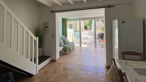 Een ruime woonkamer met een trap, een eettafel en uitzicht op het terras.