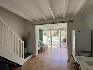 A spacious living area with a staircase, a dining table, and a view of the outdoor patio.