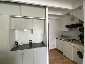 A compact kitchen with white cabinets, a microwave, a stove, and a washing machine.