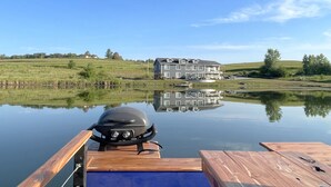 Un barco amarrado en un lago tranquilo con una casa grande al fondo.