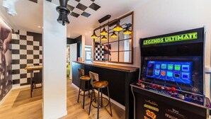 A bar area with a checkered wall, a 'Legends Ultimate' gaming machine, and two bar stools.