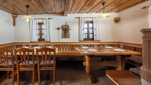 Ein Essbereich mit Holzbänken und -tischen, Holzbalken an der Decke und rustikaler Einrichtung.