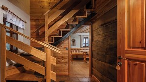 Eine Holztreppe führt zu einem Essbereich mit einer Holztür und einem kleinen Tisch mit Stühlen.