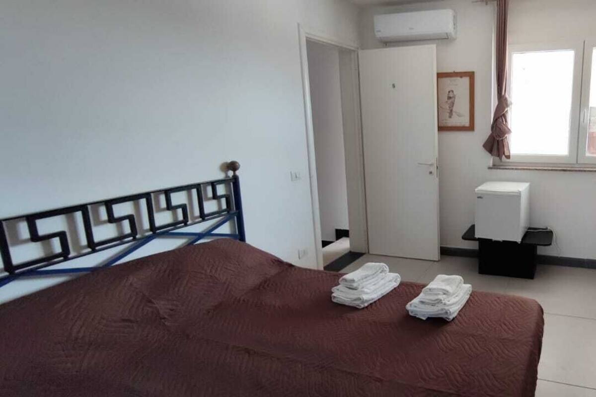 Quarto com cama, escrivaninha, janela e ar condicionado.