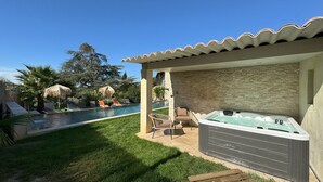 A backyard with a swimming pool, a hot tub, and a covered seating area with a stone wall backdrop. - Holiday rental with pool SAINT CHAMAS LS7-440. (Saint-Chamas)