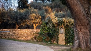A stone wall with a small arched niche, surrounded by greenery and trees. - Holiday rental with pool SAINT CHAMAS LS7-440. (Saint-Chamas)