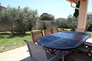 A patio with a round table and chairs, surrounded by olive trees and a stone wall. - Vacation rental house with pool AUREILLE LS1-439 (Aureille)