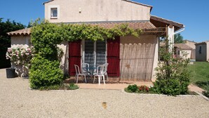 A two-story house with a patio area featuring a table and chairs, surrounded by greenery and a gravel driveway. - Vacation rental house with pool AUREILLE LS1-439 (Aureille)