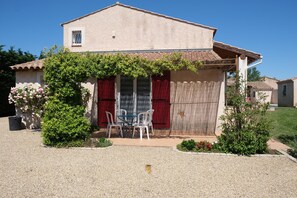 A two-story house with a patio area featuring a table and chairs, surrounded by greenery and a gravel driveway. - Vacation rental house with pool AUREILLE LS1-439 (Aureille)