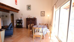 A dining area with a round table, chairs, a blue sofa, and a cabinet. - Vacation rental house with pool AUREILLE LS1-439 (Aureille)