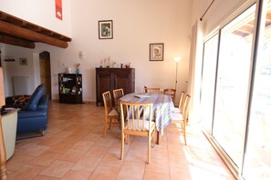 A dining area with a round table, chairs, a blue sofa, and a cabinet. - Vacation rental house with pool AUREILLE LS1-439 (Aureille)
