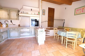 A kitchen with white cabinets, a built-in oven, and a dining area with a table and chairs.