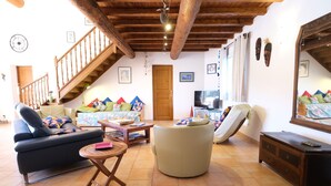 A living room with a sofa, armchair, and a small table. There is a wooden staircase and a door in the background. - Vacation rental house with pool AUREILLE LS1-439 (Aureille)