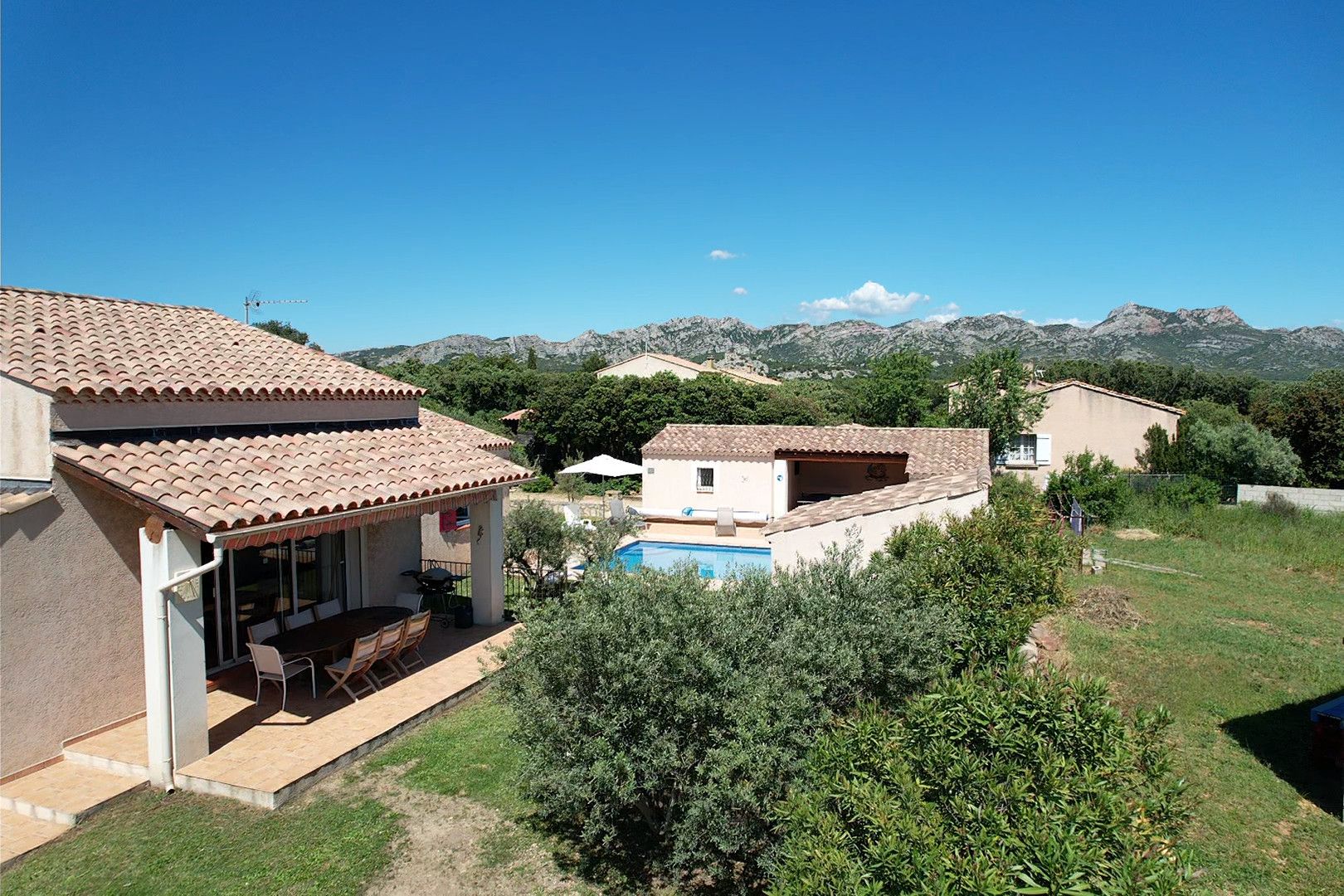 Una zona residencial con piscina, un patio amueblado al aire libre y vistas a montañas al fondo.