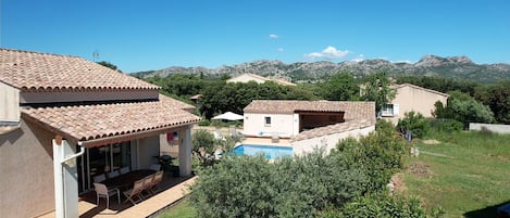 Una zona residencial con piscina, un patio amueblado al aire libre y vistas a montañas al fondo.