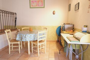 A dining area with a round table covered by a patterned tablecloth, surrounded by wooden chairs. - Vacation rental house with pool AUREILLE LS1-439 (Aureille)