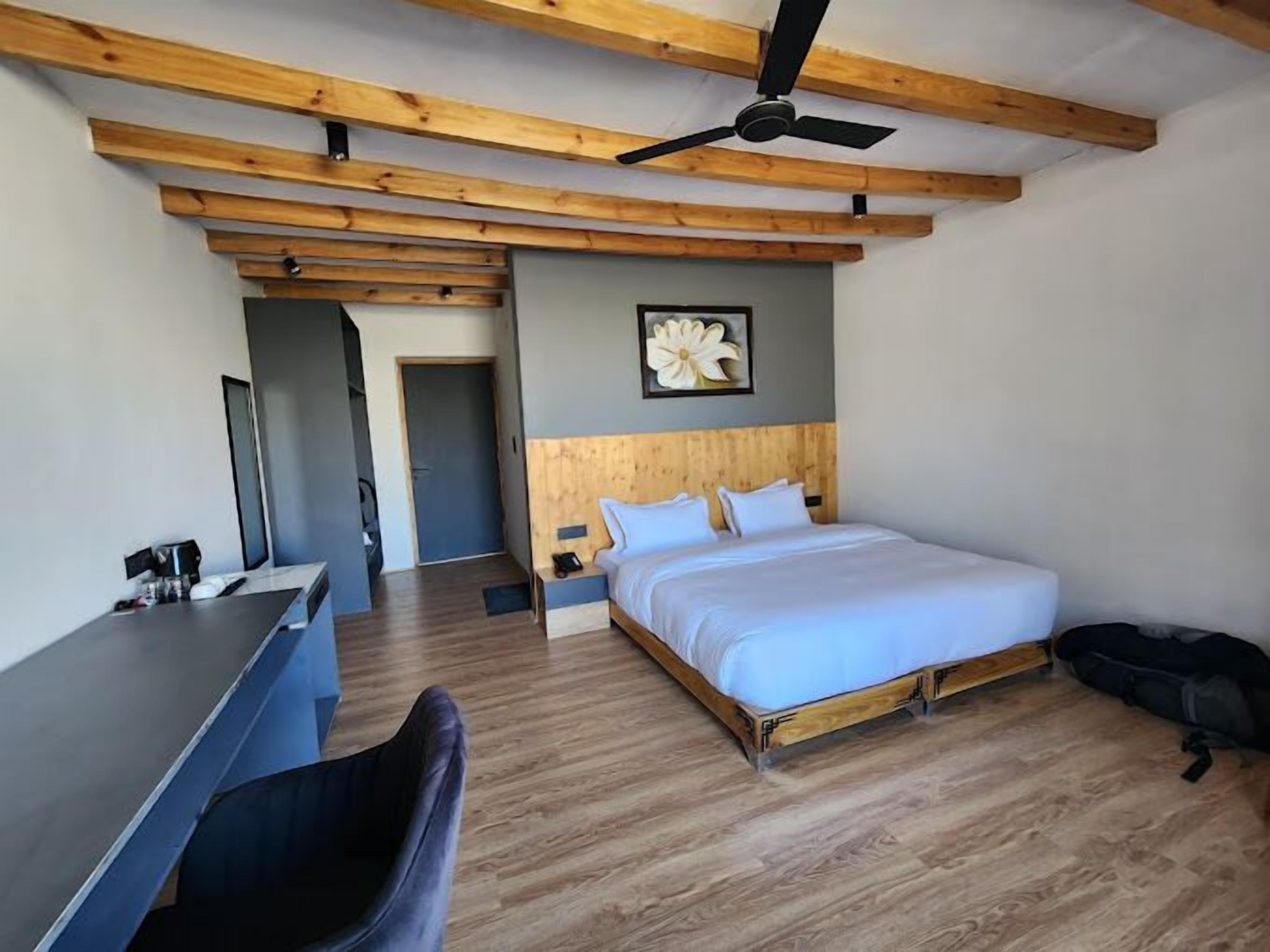 Ett modernt hotellrum med ett träpanelat tak, en säng, ett skrivbord och en stol.