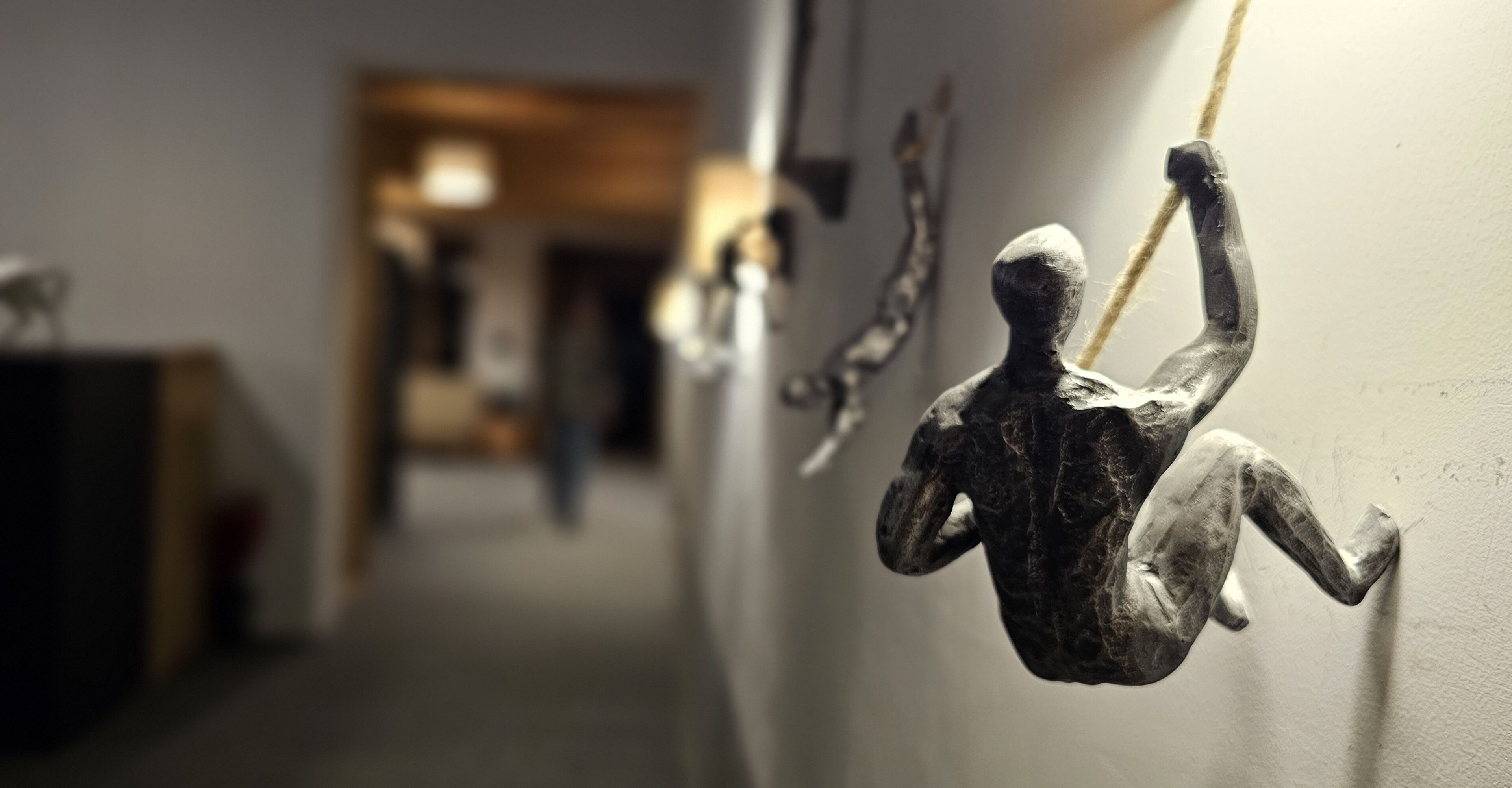 A hallway with a sculpture of a figure hanging from the wall.