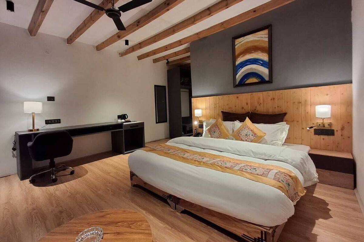 Une chambre moderne avec un grand lit, une tête de lit en bois et un ventilateur de plafond.
