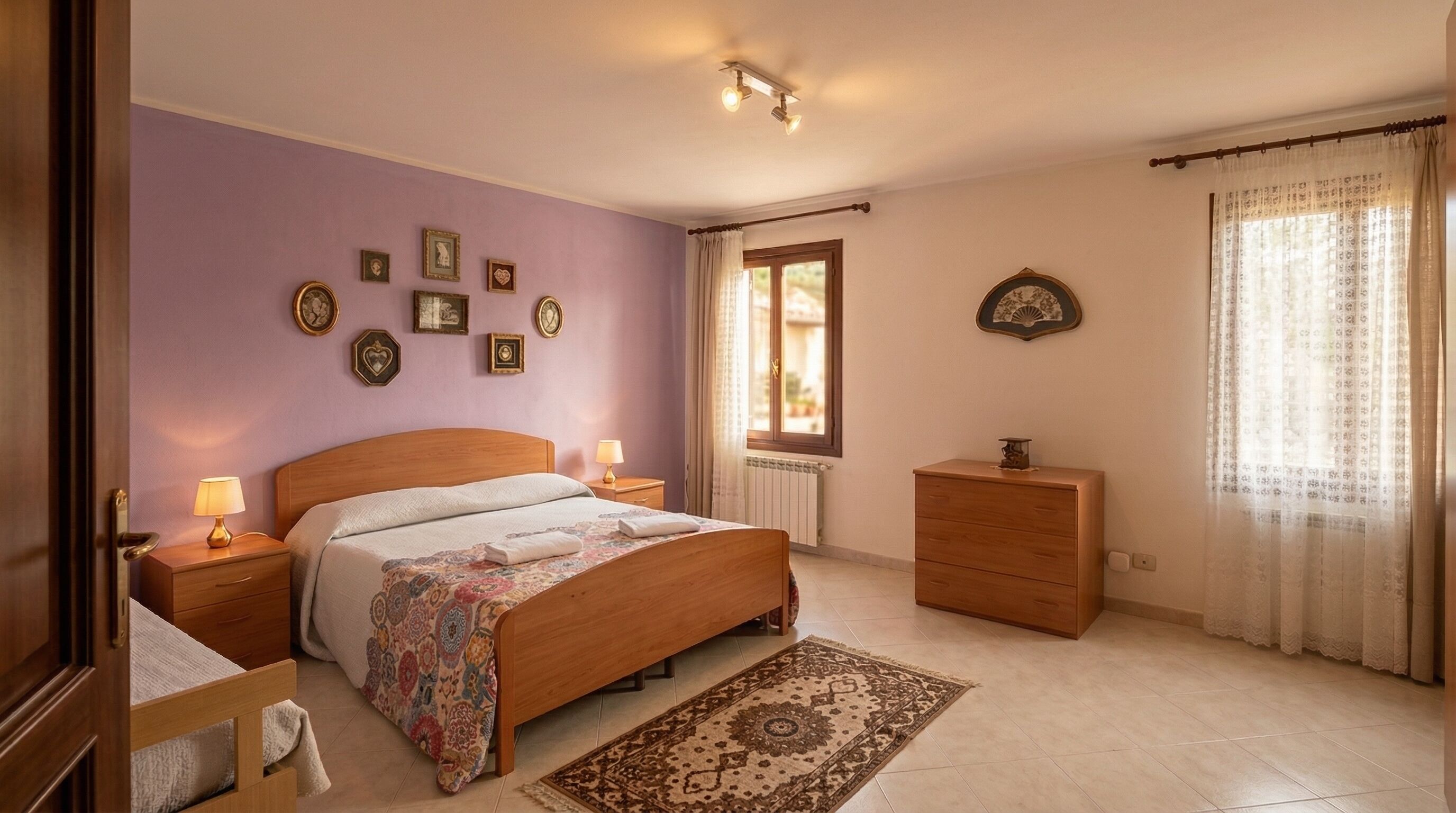 Une chambre à coucher avec un lit en bois, des tables de chevet, une commode, un tapis à motifs et des tableaux encadrés accrochés au mur.