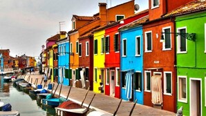 Filare di edifici colorati lungo un canale con barche ormeggiate.