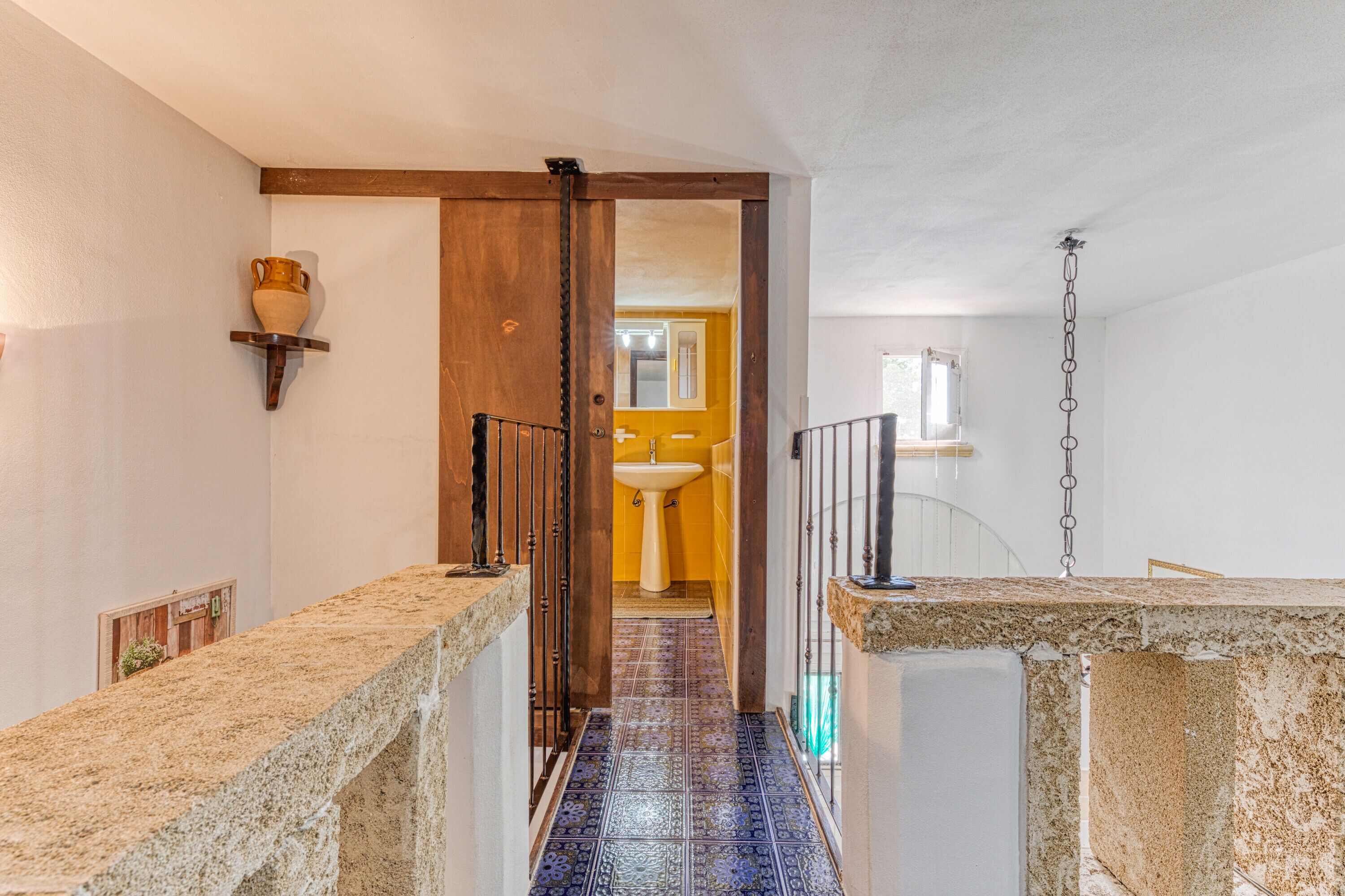 A narrow hallway with a tiled floor leading to a bathroom.