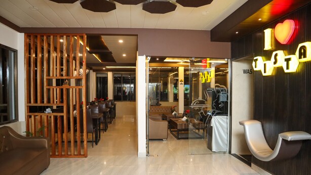 Un hall d’hôtel moderne avec un comptoir d’accueil, un espace salon et une pancarte indiquant « J’♥ TISTA ».
