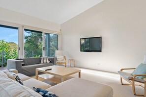 Una sala de estar moderna con un sofá, una mesa de centro y un televisor montado en la pared.