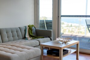 Una sala de estar moderna con un sofá, una mesita y vistas amplias a través de un gran ventanal.